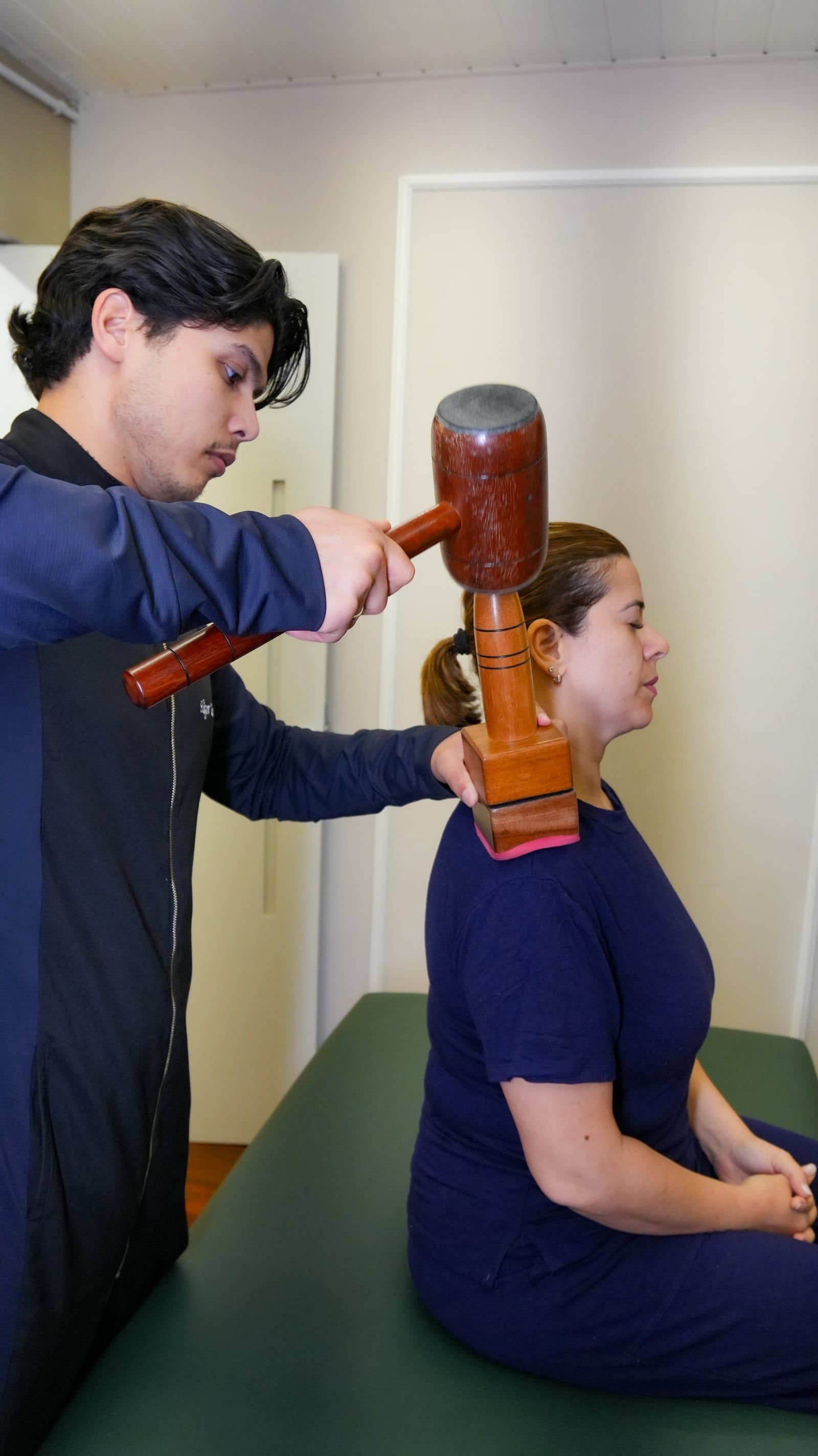 Higor Couto aplicando New Seitai na região do pescoço e dos ombros de uma paciente sentada
